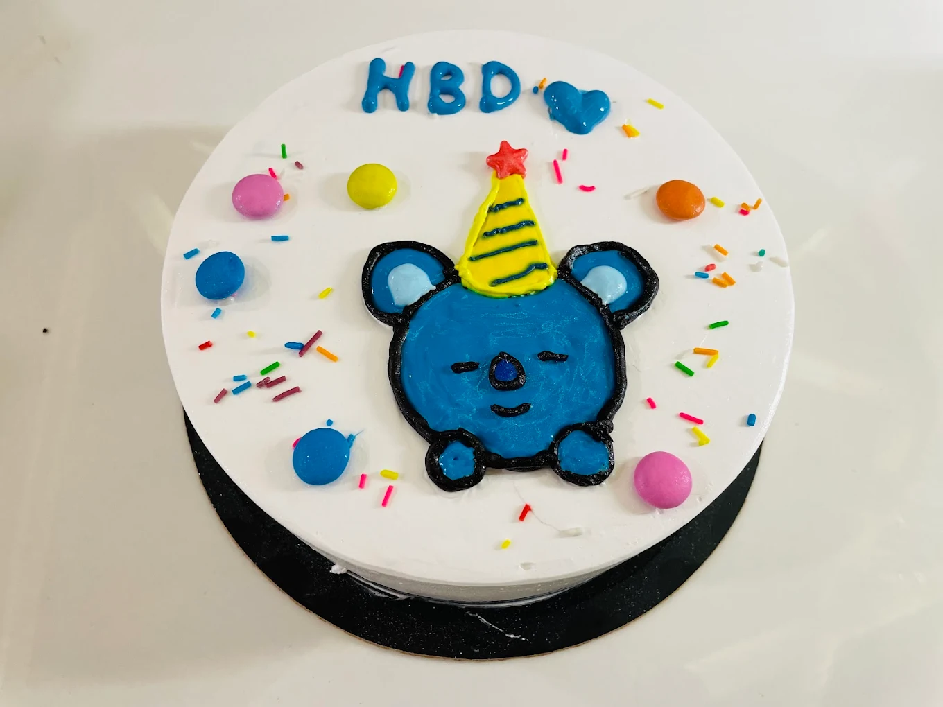 Cute koala character birthday cake with colorful sprinkles