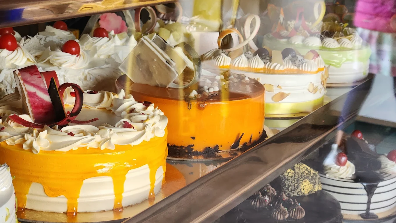 Assorted cakes in bakery display — butterscotch, mango, and fruit
